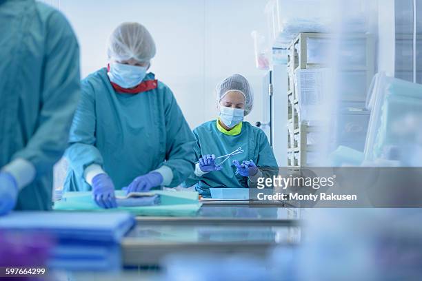 workers inspecting surgical instruments in clean room of surgical instruments factory - white suit - fotografias e filmes do acervo