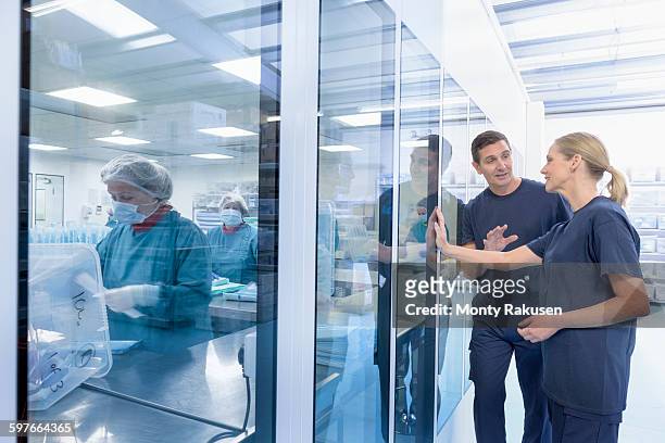workers in discussion outside clean room in surgical instrument factory - clean suit stock-fotos und bilder