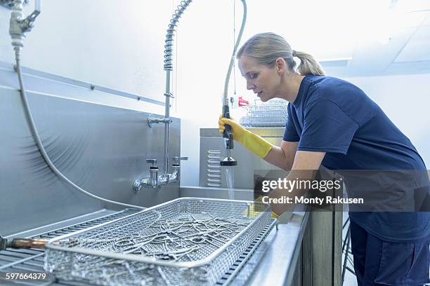 worker cleaning surgical instruments in ultrasonic bath in surgical instrument factory - surgery tools stock pictures, royalty-free photos & images