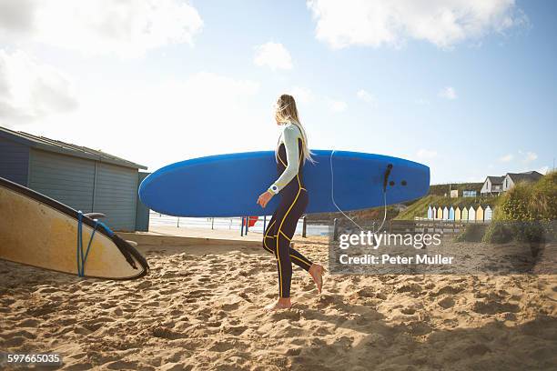 female surfer on beach, carrying surfboard - bud fotografías e imágenes de stock