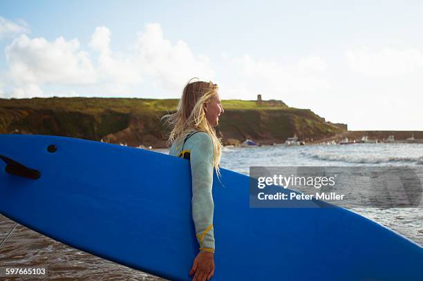 female surfer walking toward sea, carrying surfboard - bud fotografías e imágenes de stock