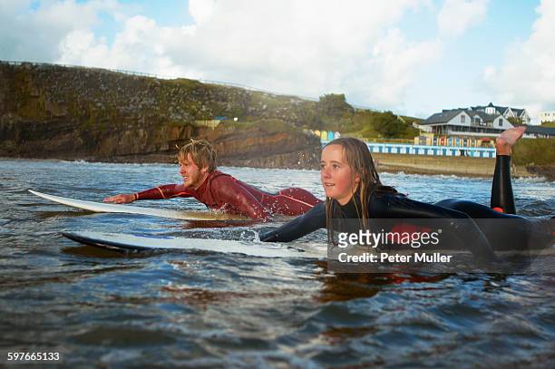 two surfers paddling on surfboards - bud fotografías e imágenes de stock