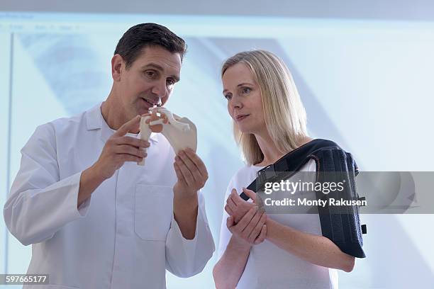 doctor fitting orthopaedic sling to patient - shoulder anatomy stock pictures, royalty-free photos & images