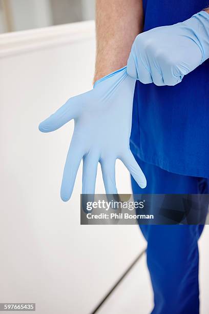 doctor putting on gloves - operating gown stock pictures, royalty-free photos & images