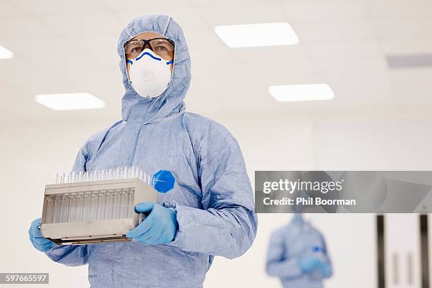 scientist carrying tray of test tubes in laboratory - macacão de limpeza imagens e fotografias de stock