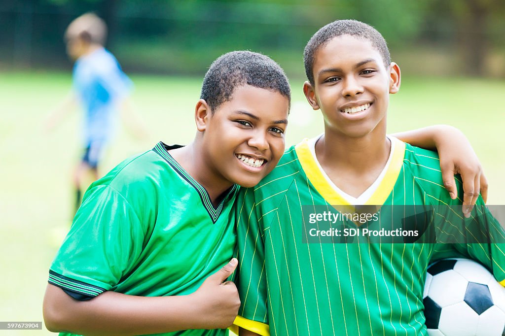 Handsome teenage soccer buddies smile proudly