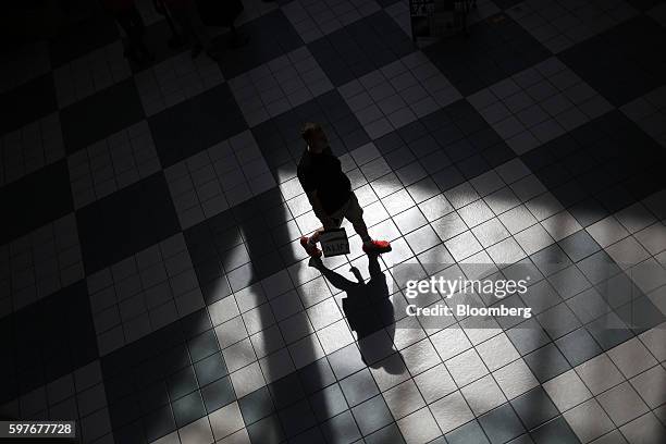 The shadow of a pedestrian carrying a shopping bag is seen on the floor tiles of the Easton Town Center shopping mall in Columbus, Ohio, U.S., on...