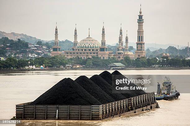 Tug pulls a coal barge past the Islamic centre on August 26, 2016 in Samarinda, Kalimantan, Indonesia. Indonesia's East Kalimantan was reported to be...