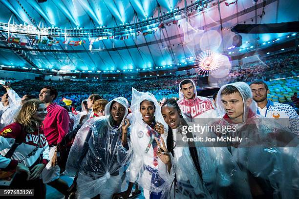 Summer Olympics: USA hurdlers Nia Ali, Kristi Castlin and Brianna Rollins pose for the camera in the rain during Parade of Athletes at Maracana...