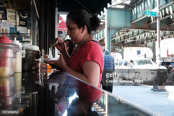 Woman eats at a taco stand in the ethnically diverse neighborhood of Queens on August 29, 2016 in New York City. Queens County is one of the five...
