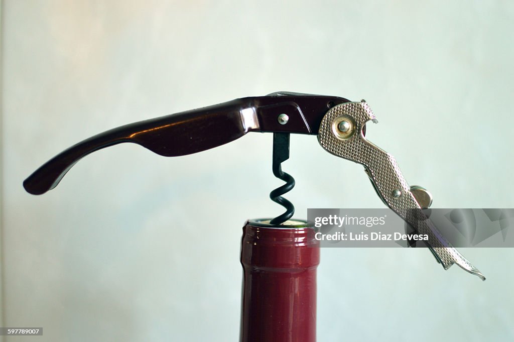 Opening bottle of wine with corkscrew