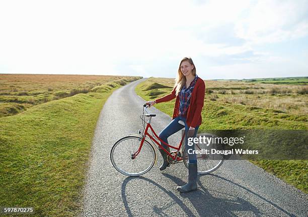 woman with red bike on country lane. - summer cardigan women stockfoto's en -beelden