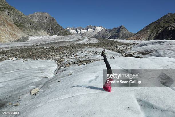 Hiker and yoga enthusiast Karin Bittel, who was participating in a guided tour across the Aletsch glacier, stands on her head on the ice of the...