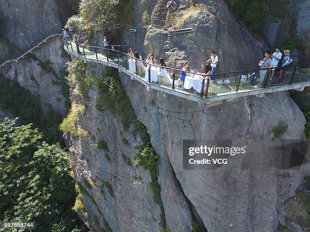 Aerial view of visitors enjoying desserts at an outdoor dining hall on Shiniuzhai's glass-bottomed bridge in Pingshan County on August 29, 2016 in...