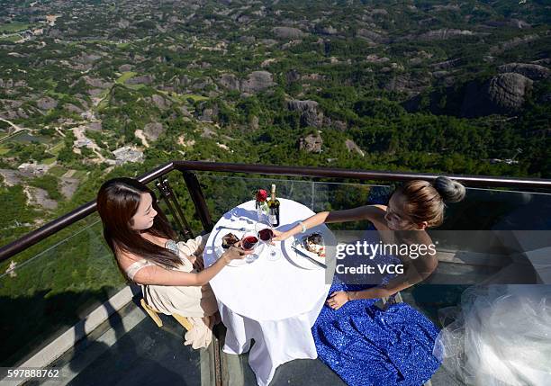 Aerial view of visitors enjoying desserts at an outdoor dining hall on Shiniuzhai's glass-bottomed bridge in Pingshan County on August 29, 2016 in...