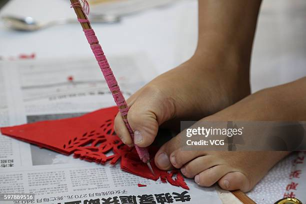 Armless girl Xia Hong carves paper-cutting with her feet during a handcraft competition on August 29, 2016 in Beijing, China. 232 participants...
