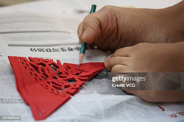 Armless girl Xia Hong traces on red paper with her feet during a handcraft competition on August 29, 2016 in Beijing, China. 232 participants...