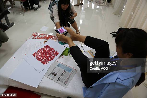 Armless girl Xia Hong takes pictures of herself paper-cutting with her feet during a handcraft competition on August 29, 2016 in Beijing, China. 232...