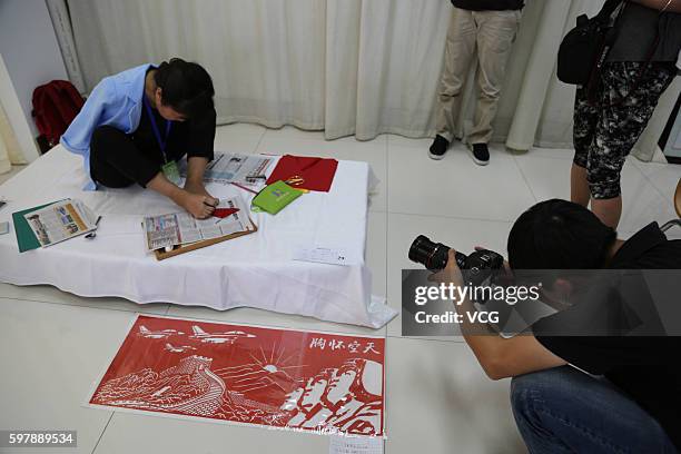 Photographer shoots armless girl Xia Hong tracing on red paper with her feet during a handcraft competition on August 29, 2016 in Beijing, China. 232...