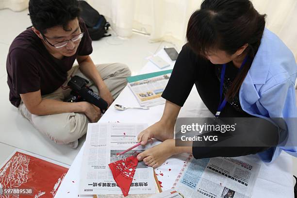 Armless girl Xia Hong carves paper-cutting with her feet during a handcraft competition on August 29, 2016 in Beijing, China. 232 participants...