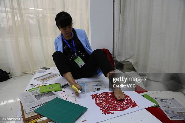 Armless girl Xia Hong fixes her paper-cutting with glue stick during a handcraft competition on August 29, 2016 in Beijing, China. 232 participants...
