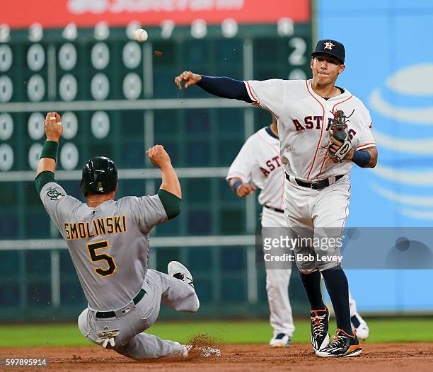 Carlos Correa of the Houston Astros throws over Jake Smolinski of the Oakland Athletics to complete a double play in the third inning at Minute Maid...
