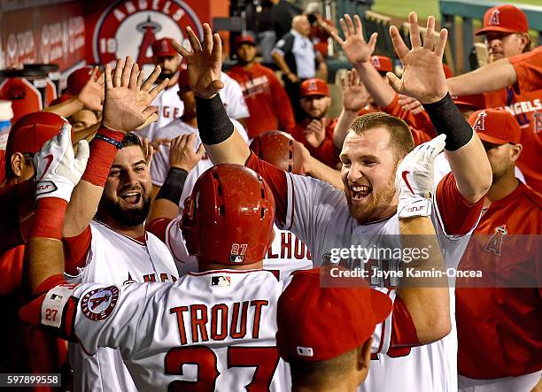 Mike Trout of the Los Angeles Angels is greeted in the dugout by Jett Bandy and Rafael Ortega after hitting a 2 run home run in the first inning of...