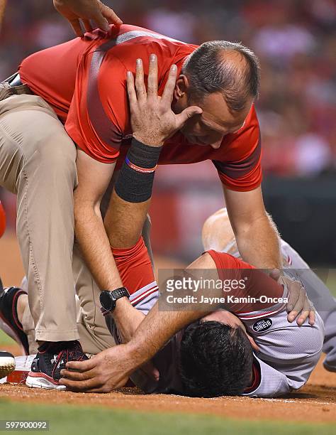 Jose Peraza of the Cincinnati Reds gets attention from medical personnel after getting hit on the head from a pick off play by Matt Shoemaker of the...