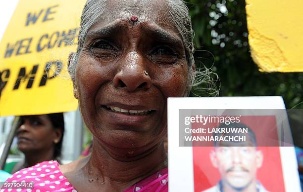 Group of women hold up images of their family members who had disappeared during the civil war with the Liberation Tigers of Tamil Eelam at a silent...