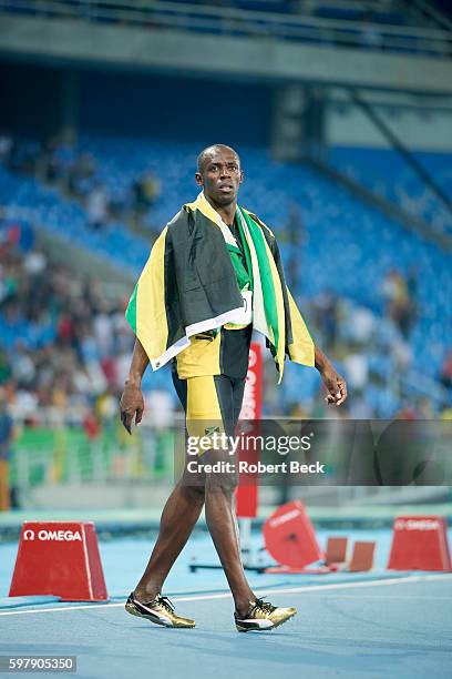 Summer Olympics: Jamaica Usain Bolt victorious, wearing Jamaican flag after winning gold medal in Men's 4x100M Relay Final at Rio Olympic Stadium....