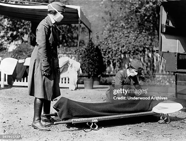 Two Red Cross nurses with a person on a stretcher during a demonstration at the Red Cross Emergency Ambulance Station during the influenza pandemic...