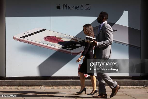 Pedestrians walk past advertising for Apple Inc's iPhone 6S outside an O2, the British mobile unit of Telefonica SA, store in London, U.K., on...