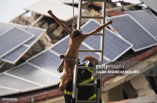 Firefighter fixes a crucifix in Amatrice, central Italy, on August 30 prior to a funeral ceremony for the victims of a recent earthquake. The deadly...