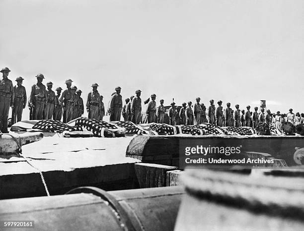 Troops stand at attention behind the flag draped coffins of their countrymen killed in the battle of Midway, Midway Island, June 1942.