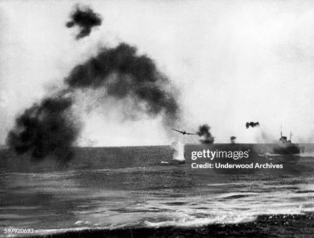 Smoke and waterspouts from falling bombs obscure a US Navy ship at the right during a Japanese aerial attack during the battle of Midway Island,...