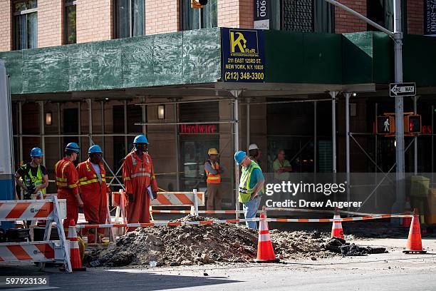 Workers observe the site of a water main break that caused a sinkhole on Amsterdam Avenue, in the Upper West Side section of Manhatten, August 30,...