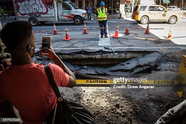 Pedestrian takes a photo of sinkhole caused by a water main break on Amsterdam Avenue, in the Upper West Side section of Manhatten, August 30, 2016...