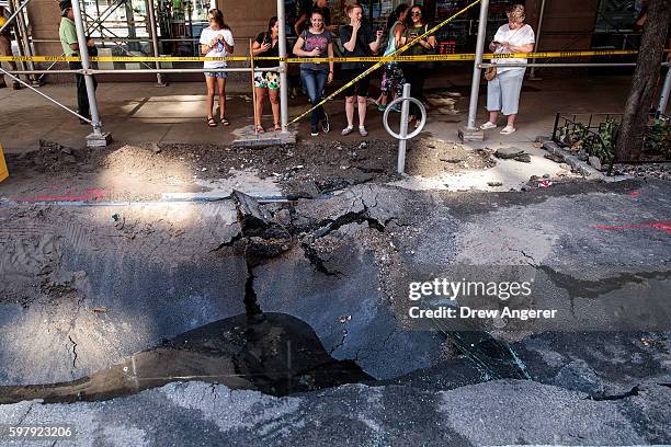 Pedestrians stop and look at a sinkhole caused by a water main break on Amsterdam Avenue, in the Upper West Side section of Manhatten, August 30,...