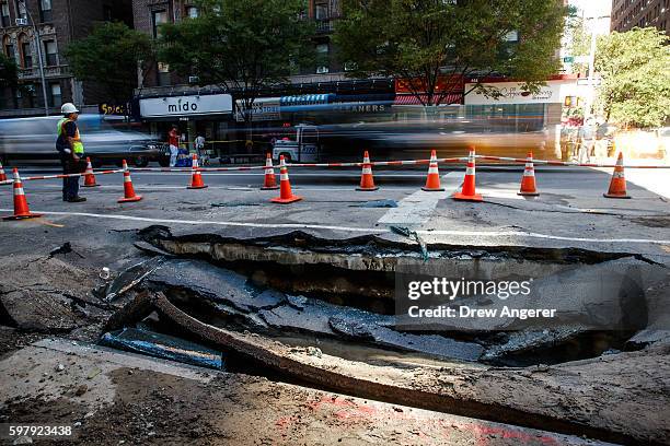 Traffic passes by a sinkhole caused by a water main break on Amsterdam Avenue, in the Upper West Side section of Manhatten, August 30, 2016 in New...