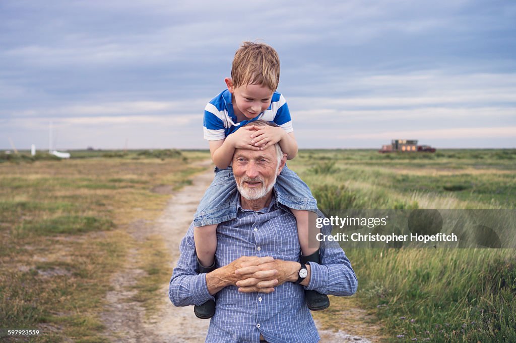 Young boy being carried by his grandad