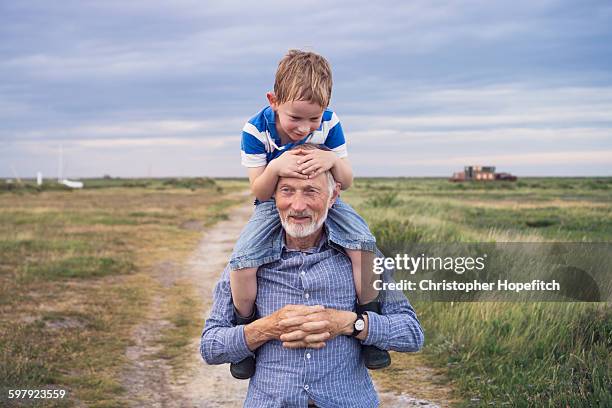 young boy being carried by his grandad - abuelos fotografías e imágenes de stock