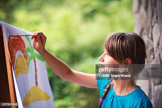 little girl painting on easel in the garden - young artist stock pictures, royalty-free photos & images