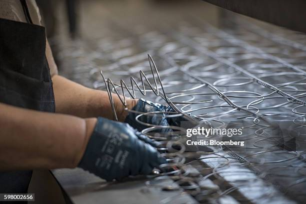 Worker assembles inner spring units for a mattress at the McRoskey Mattress Co. Facility in San Francisco, California, U.S., on Tuesday, Aug. 30,...