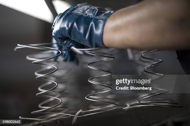 Worker assembles inner spring units for a mattress at the McRoskey Mattress Co. Facility in San Francisco, California, U.S., on Tuesday, Aug. 30,...