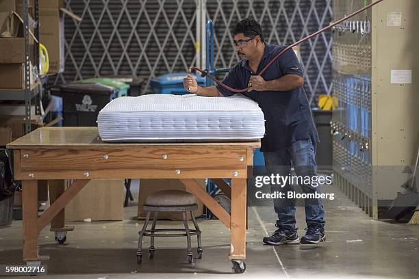 Worker cleans a mattress prior to being shipped at the McRoskey Mattress Co. Facility in San Francisco, California, U.S., on Tuesday, Aug. 30, 2016....