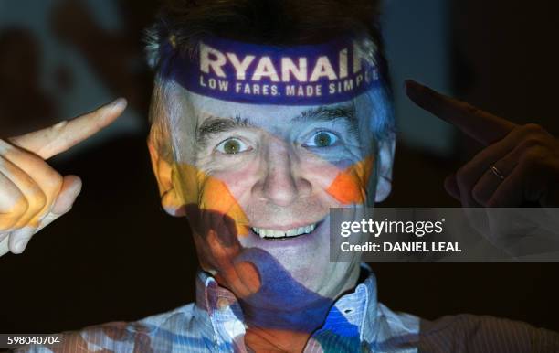 Chief Executive Officer of Irish airline Ryanair Michael O'Leary poses with his company's logo projected on his face as he attends a press conference...