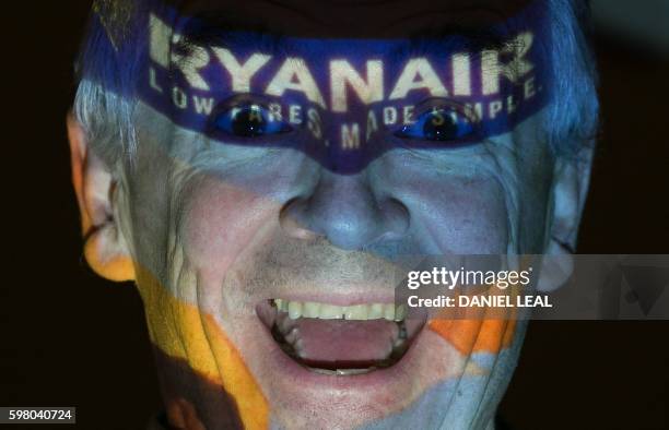 Chief Executive Officer of Irish airline Ryanair Michael O'Leary poses with his company's logo projected on his face as he attends a press conference...