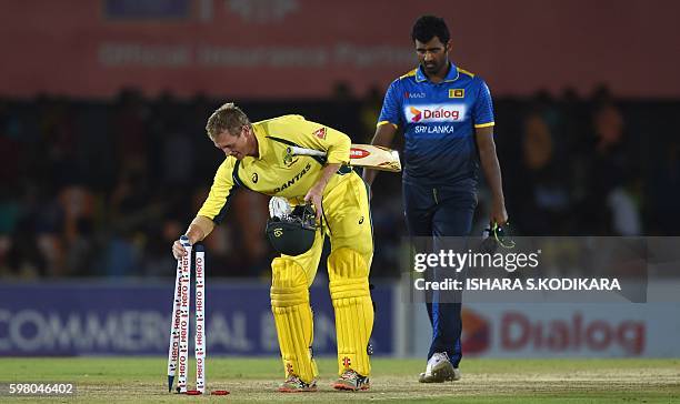 Australian cricketer George Bailey leaves the grounds with the stumps after victory in the fourth one day international as Sri Lankan cricketer...