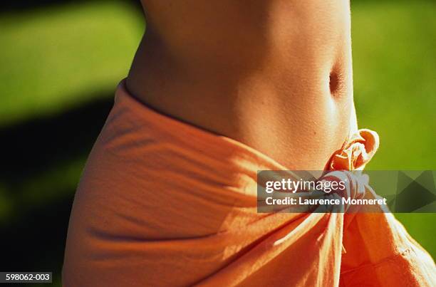 woman wearing orange sarong, close-up of midriff - navel orange stockfoto's en -beelden