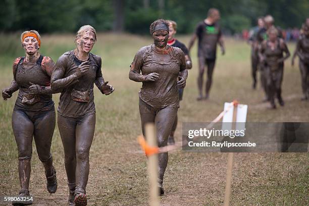 three muddy women running - tough mudder imagens e fotografias de stock